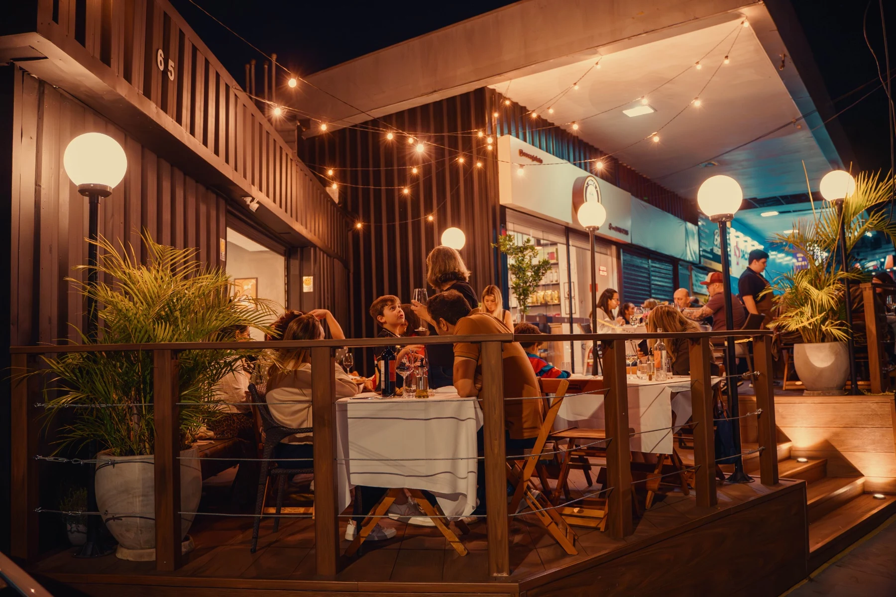 Deck do SOCA à noite com mesas, plantas e iluminação acolhedora