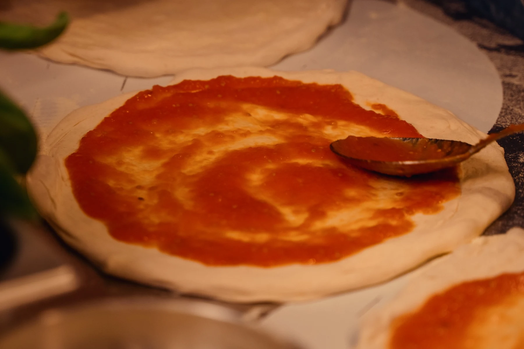 Molho de tomate sendo espalhado sobre a massa