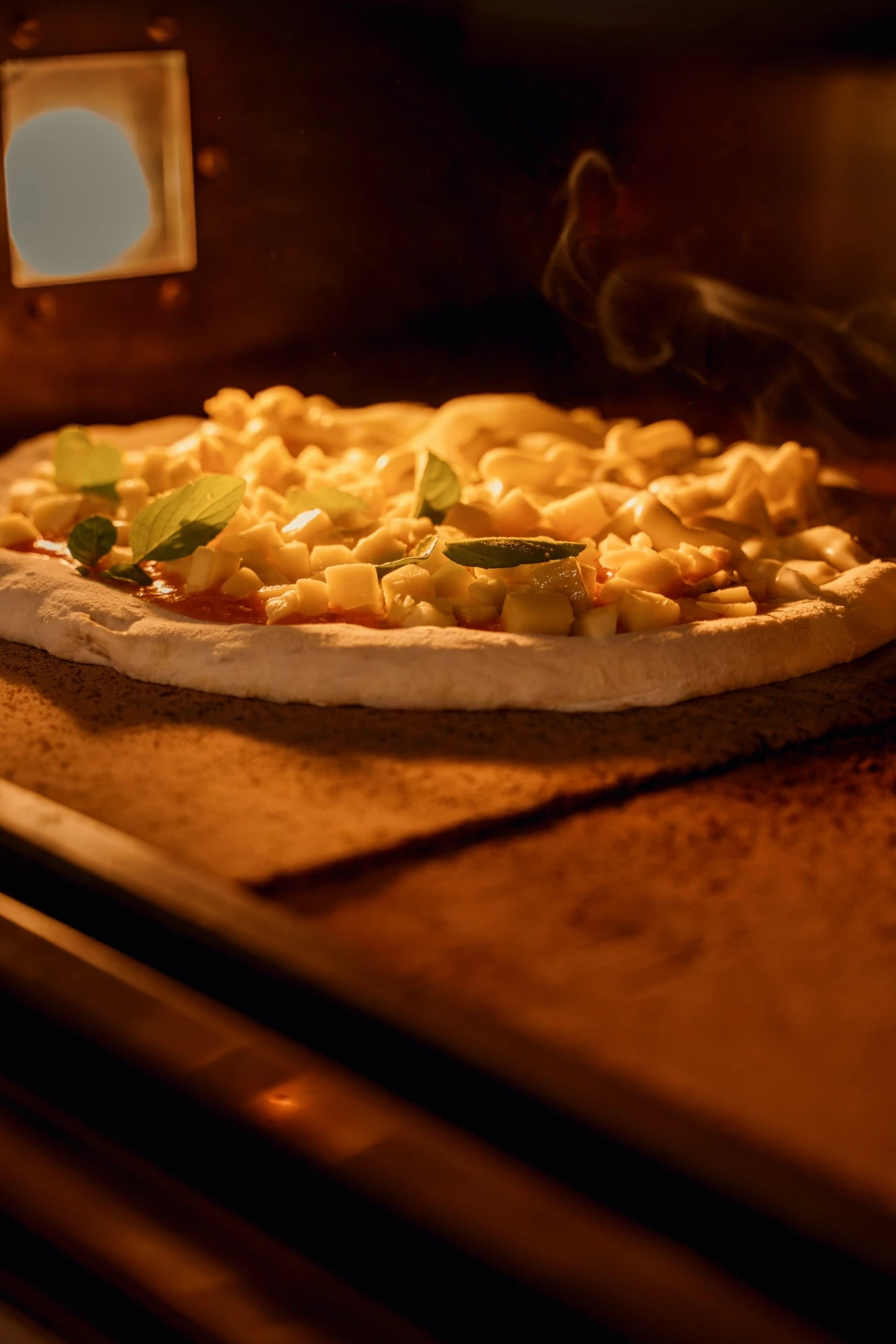 Pizza com queijo e manjericão assando no forno